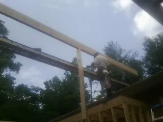 Carpenter setting a ridge beam over a new addition frame — Ice Dam Removal by Roofing Brothers in Ellenboro