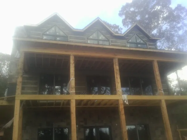 Dormers and porch framing on a large log home under construction — Roof Coating work by our crew in Ellenboro