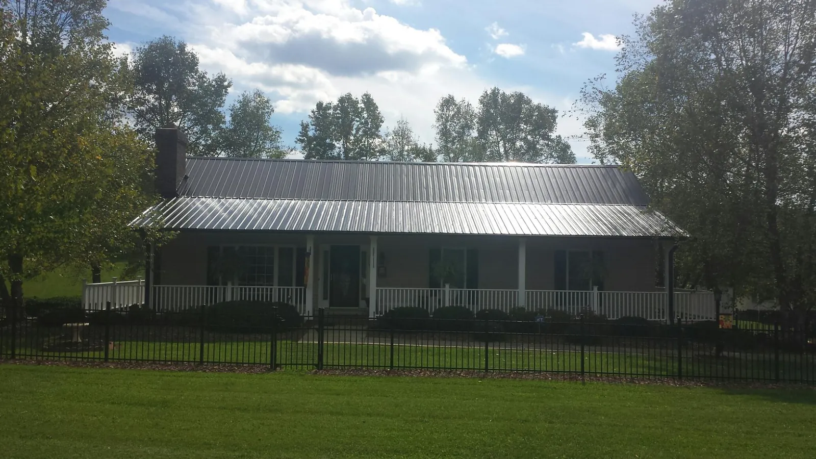 Gray metal roof on a brick ranch with a full width front porch — Gutter Guard Installation work by our crew in Ellenboro