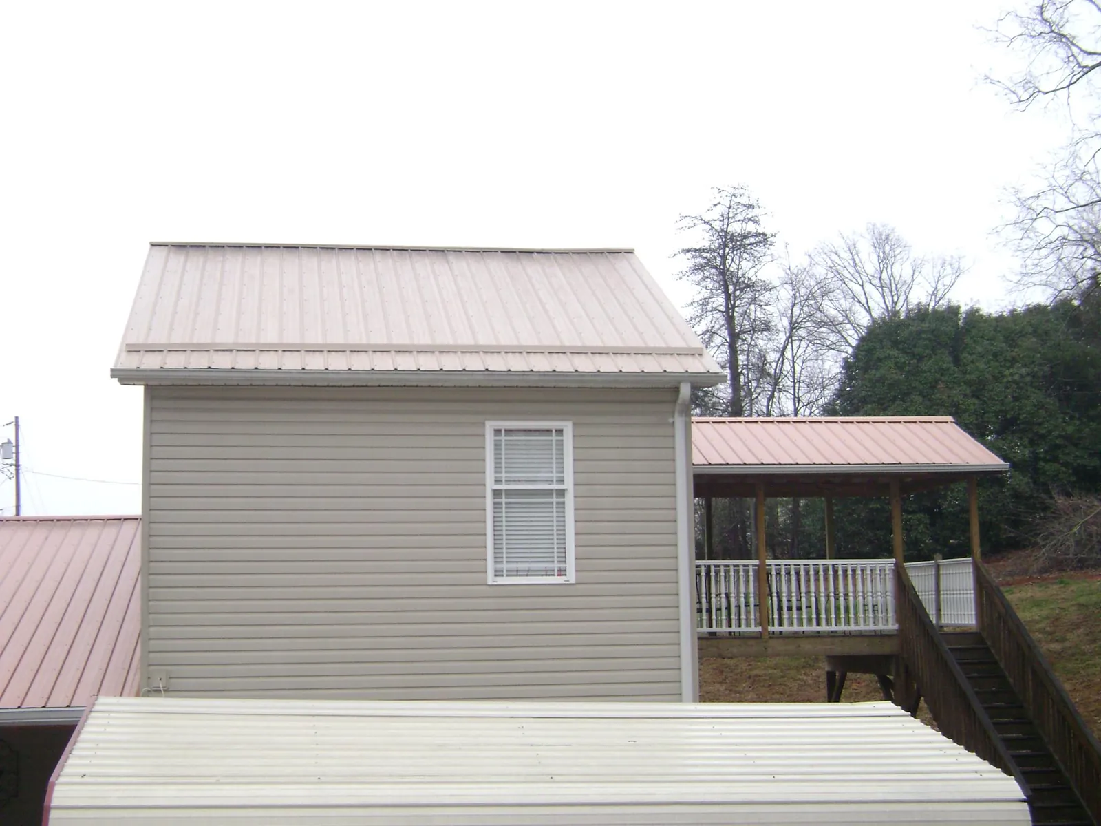 Tan metal roofs on a two story addition and attached porch in Ellenboro