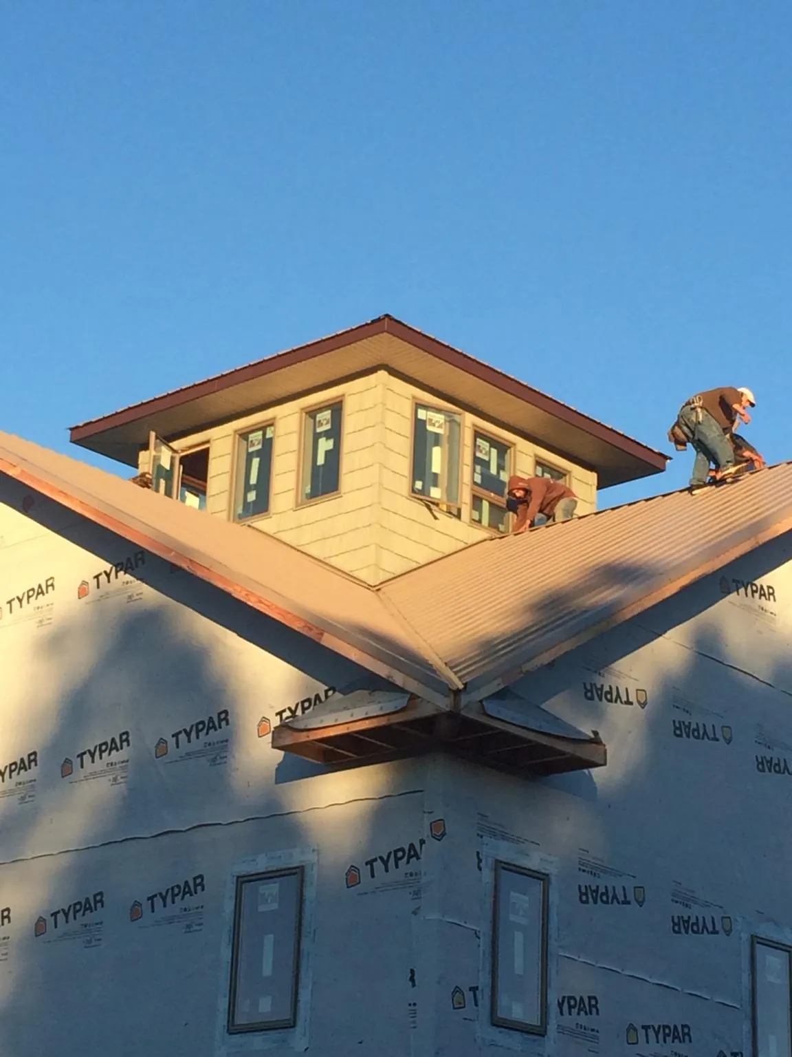 Roofers working around a rooftop cupola on a new metal roof at sunset — Roof Waterproofing in Ellenboro by Roofing Brothers